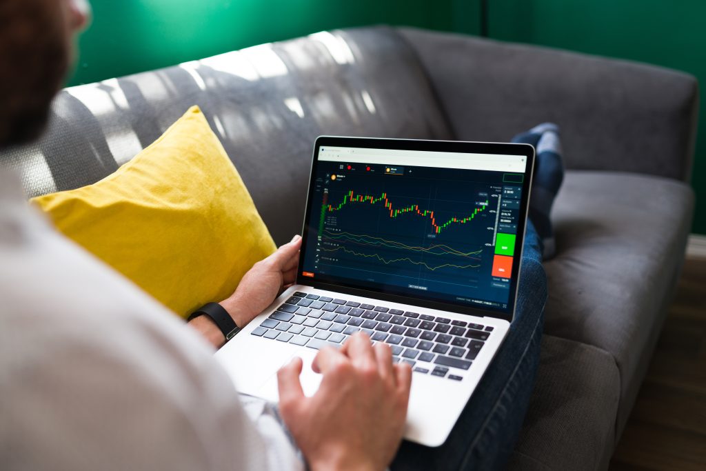 trading finances young man resting couch while checking stock market laptop